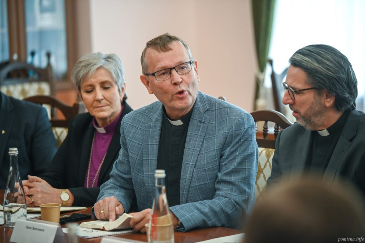 Члени норвезької делегації за столом, серед них єпископ у фіолетовій сорочці